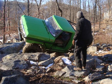 1978 Ford Bronco - A green off-road vehicle navigates a rocky terrain, with another vehicle visible in the background.