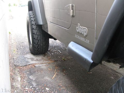 1987 Suzuki Samurai - Close-up of a Jeep Scrambler's side panel, showing the 'Jeep' and 'SCRAMBLER' badging.