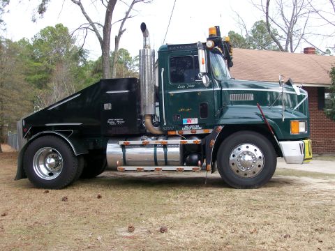 1996 Ford Bronco - Side view of a green semi-truck a custom black rear body and chrome exhaust.