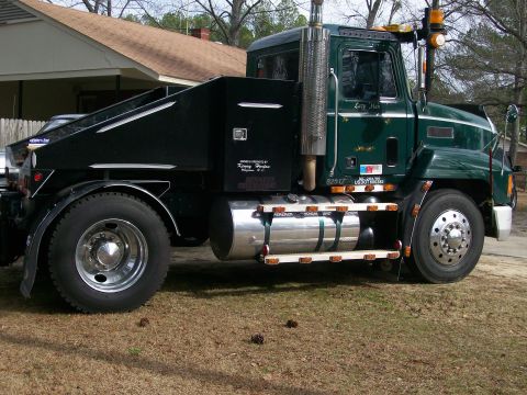 1996 Ford Bronco - A green tow truck with chrome details is parked on a grassy area in front of a house.