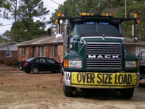 1996 Ford Bronco - A green Mack truck is parked in front of a house with a black sedan nearby.
