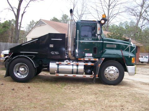 1996 Ford Bronco - A green semi-truck with a custom black bed and prominent chrome exhaust stacks is parked outdoors.