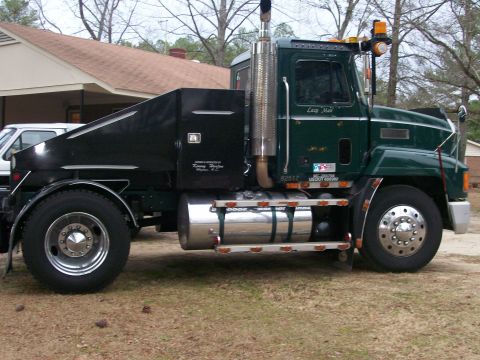 1996 Ford Bronco - Side view of a green semi-truck a black utility body and chrome fuel tank.