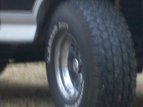 1996 Ford Bronco - Close-up view of a vehicle's wheel and tire, with text visible on the tire's sidewall.