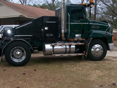 1996 Ford Bronco - Side view of a custom green semi-truck a black sleeper box and chrome fuel tanks.
