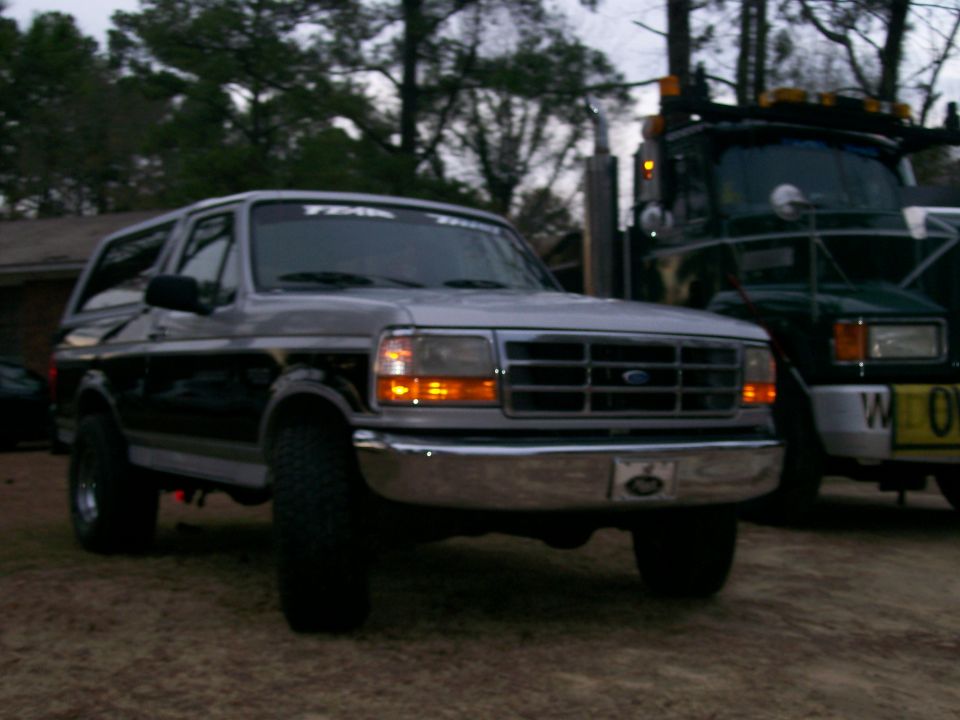 1996 Ford Bronco parked next to a tow truck