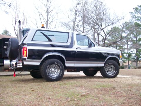 1996 Ford Bronco - Side profile of a two-tone 1996 Ford Bronco with a spare tire on the back.