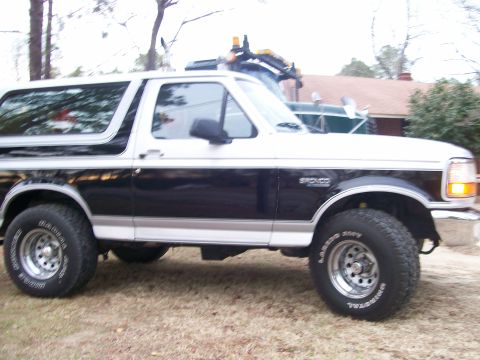 1996 Ford Bronco - This two-tone Ford Bronco is parked outdoors with another vehicle in the background.