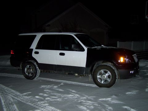 2004 Ford Expedition - This two-tone SUV, likely a 2004 Ford Expedition, is parked on a snowy surface at night.