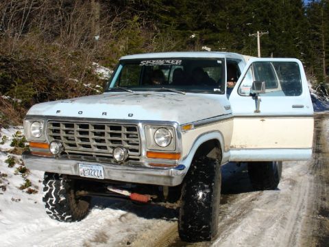 1978 Ford Bronco - A light blue and cream 1978 Ford Bronco sits on a snowy dirt road with its driver's door ajar.
