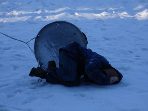 1978 Ford Bronco - A person is kneeling in the snow next to a large metal object, with a rope attached.