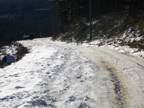 1978 Ford Bronco - A snowy mountain road with two trucks in the distance.