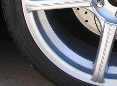 1993 Ford Taurus - Close-up of a silver alloy wheel with stamped markings and a visible brake rotor.