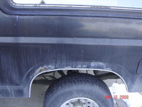 1985 Ford Bronco - Close-up of the rear wheel well on a 1985 Ford Bronco, showing signs of rust.