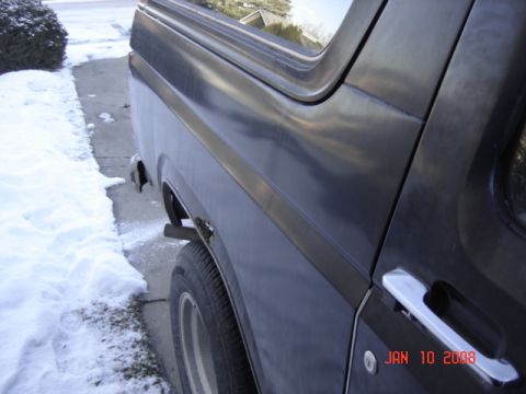 1985 Ford Bronco - A dark gray 1980s Ford Bronco is seen from the side, parked next to a snowy driveway.