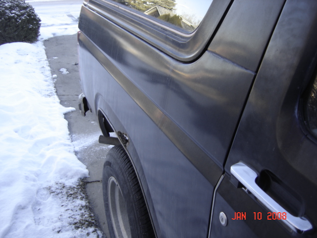 Dark gray 1980s Ford Bronco side view, showing rear wheel well and door handle