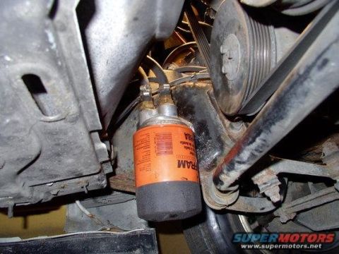1986 Ford Bronco - Close-up view of an orange FRAM transmission filter attached to hoses and engine components.