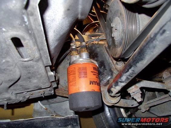 Orange FRAM transmission filter with black end cap, part of engine assembly