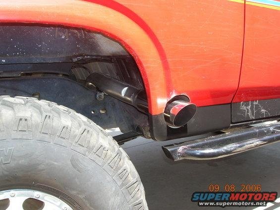 Close-up of a red vehicle's rear tire and exhaust pipe exiting the body