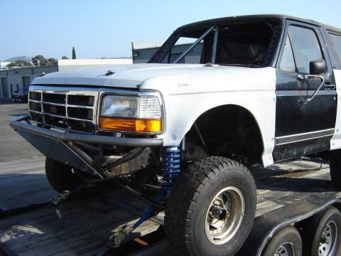 1986 Ford Bronco - This modified Ford Bronco features a roll cage and custom bumper, with its front end visible on a trailer.