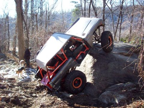 1978 Ford Bronco - This heavily modified off-road vehicle is navigating a challenging rocky terrain with assistance from onlookers and canine companions.