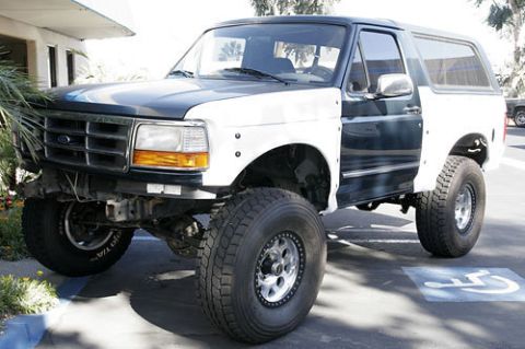 1986 Ford Bronco - This lifted Ford Bronco has a dark blue and white two-tone paint scheme and aftermarket wheels.