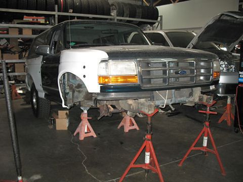 1986 Ford Bronco - This Ford Bronco, likely from the early to mid-1990s, is elevated on jack stands with its front end partially disassembled for repair.