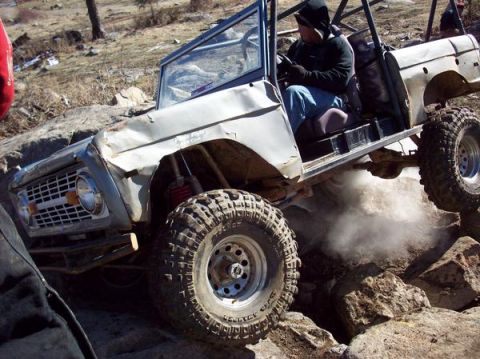 1978 Ford Bronco - This heavily modified SUV is navigating a rocky, off-road course, kicking up dust.
