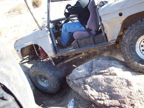1978 Ford Bronco - A modified 1978 Ford Bronco navigates a rocky terrain, with its front tire angled over a large boulder.
