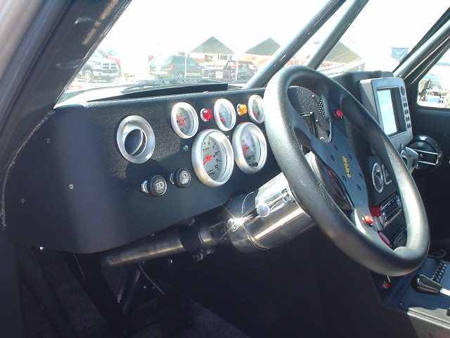 Custom dashboard with multiple gauges, aftermarket steering wheel, and GPS unit. Roll cage visible