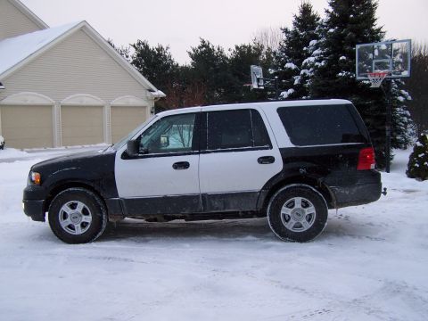 2004 Ford Expedition - A two-tone 2004 Ford Expedition sits in a snowy driveway next to a house with a basketball hoop in the background.
