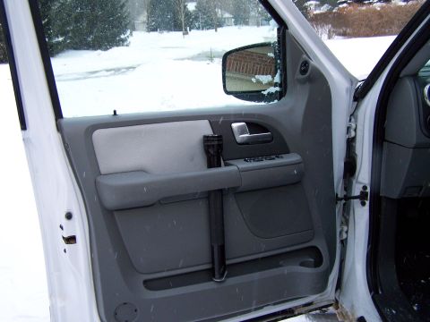 2004 Ford Expedition - Interior view of a car door panel with a flashlight and a snowy scene visible through the open door.