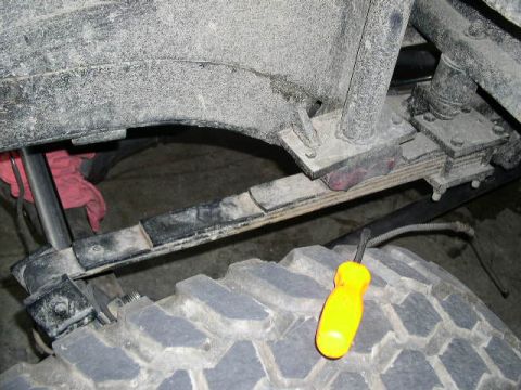 1979 Ford Bronco - Close-up view of a vehicle's tire and suspension system, with a yellow screwdriver resting on the tire.
