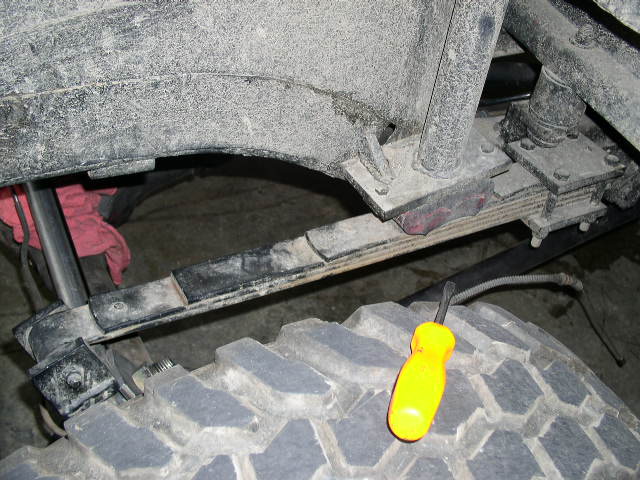 Tire and leaf spring suspension of a vehicle with a yellow screwdriver on the tire
