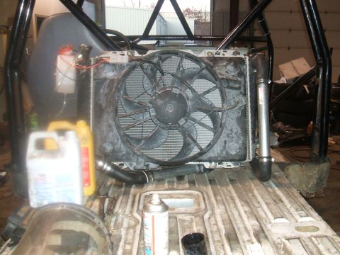 1995 Ford Bronco - A close-up view of a radiator and fan assembly, likely during a rebuild or maintenance, with fluids and tools present.