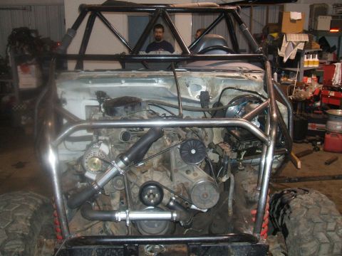 1995 Ford Bronco - This heavily modified vehicle shows its engine and custom roll cage, with a person visible in the driver's seat.