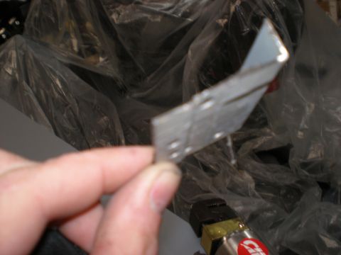 1995 Ford F-150 - A hand holds a metal bracket with multiple holes, possibly a car part.