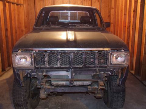 1990 Ford Bronco - This Toyota pickup truck is parked indoors, showing its front end with missing bumper components.