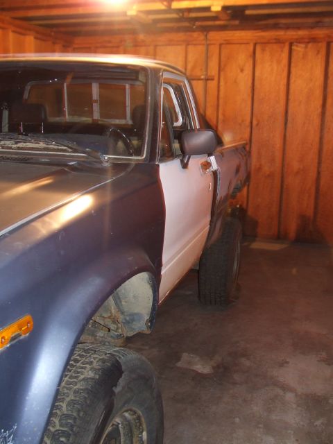 1990 Ford Bronco - A pickup truck with unfinished bodywork sits in a wooden-paneled garage.