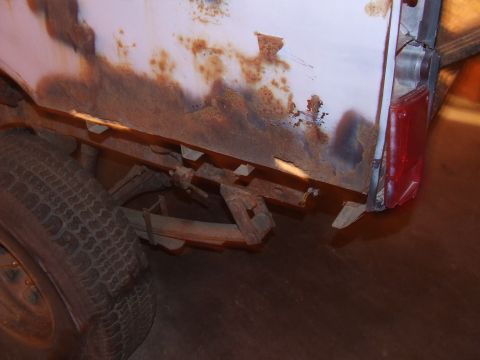1990 Ford Bronco - The rear quarter panel and tire of a vehicle show significant rust damage.