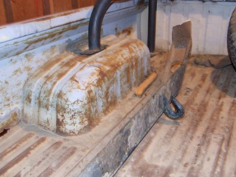 1990 Ford Bronco - The interior of a truck bed shows wear and tear with rust and dirt visible on the metal surfaces.