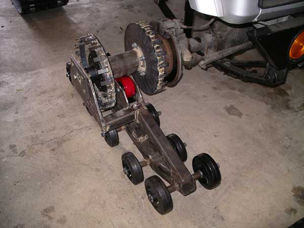 Custom welded track undercarriage with sprockets and road wheels on garage floor