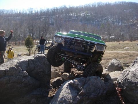 1978 Ford Bronco - A heavily modified truck navigates a challenging rocky terrain with onlookers observing the action.