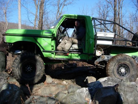 1978 Ford Bronco - Modified off-road vehicle with a prominent roll cage is shown traversing a rocky terrain.