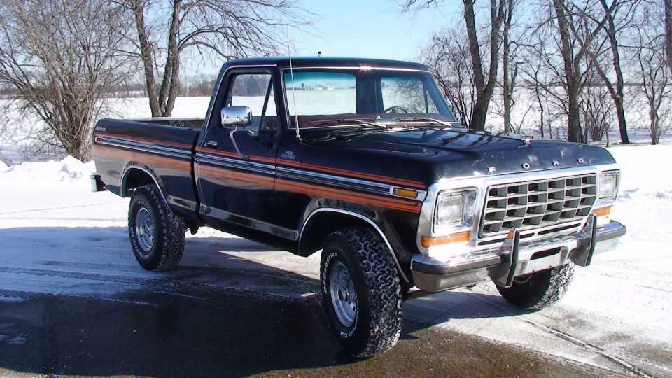 Black late-1970s Ford F-series 4x4 pickup with striped trim in snow