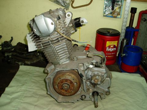 2000 Ford E350 - A disassembled motorcycle engine sits on a cloth-covered surface, with various tools and a coffee can visible behind it.
