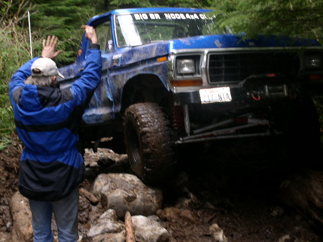 1979 Ford Bronco off-roading with a person near the driver's door