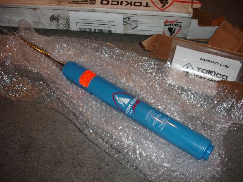 1993 Ford Taurus - A blue Tokico gas shock absorber is shown with its packaging and warranty card.