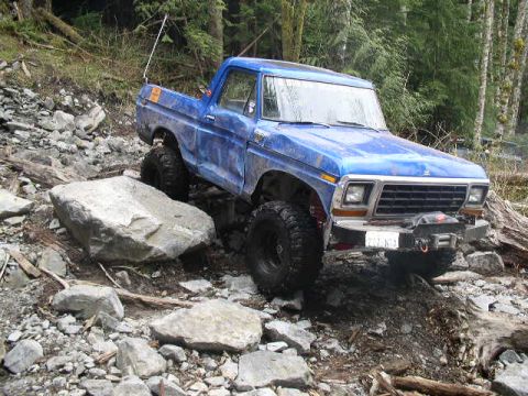 1979 Ford Bronco - This blue pickup truck navigates a challenging rocky trail, its off-road capabilities.
