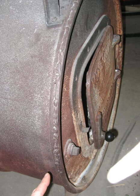 1986 Ford Ranger - Close-up of a rusty metal drum's side, revealing a hinged door and visible weld seams.